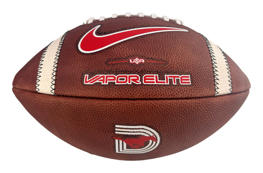 Brown American football with white laces and a red Nike swoosh, labeled Vapor Elite with USA branding.
