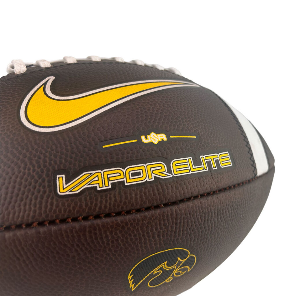 Close-up of a brown leather football with a yellow Nike swoosh and 'Vapor Elite' branding.