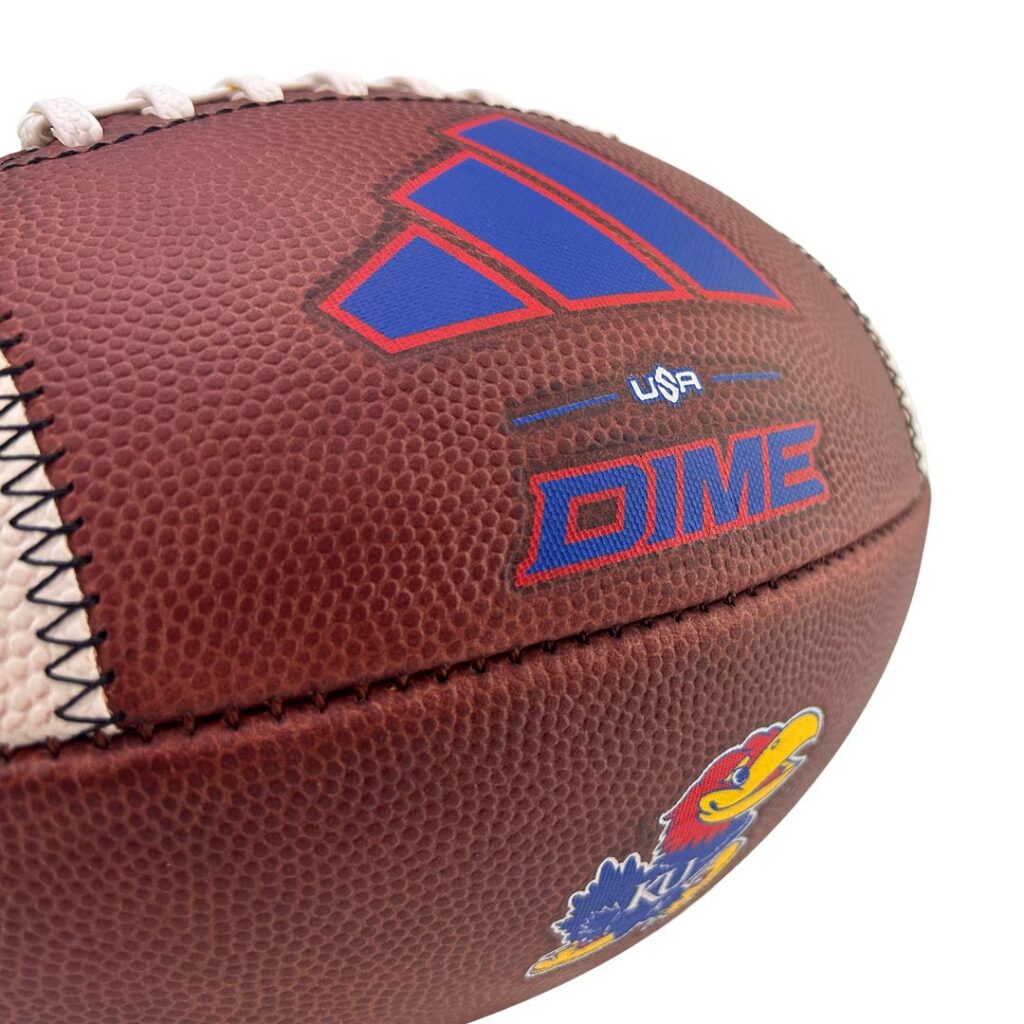 Close-up of a brown leather football with blue and red logo and a Kansas Jayhawks sticker