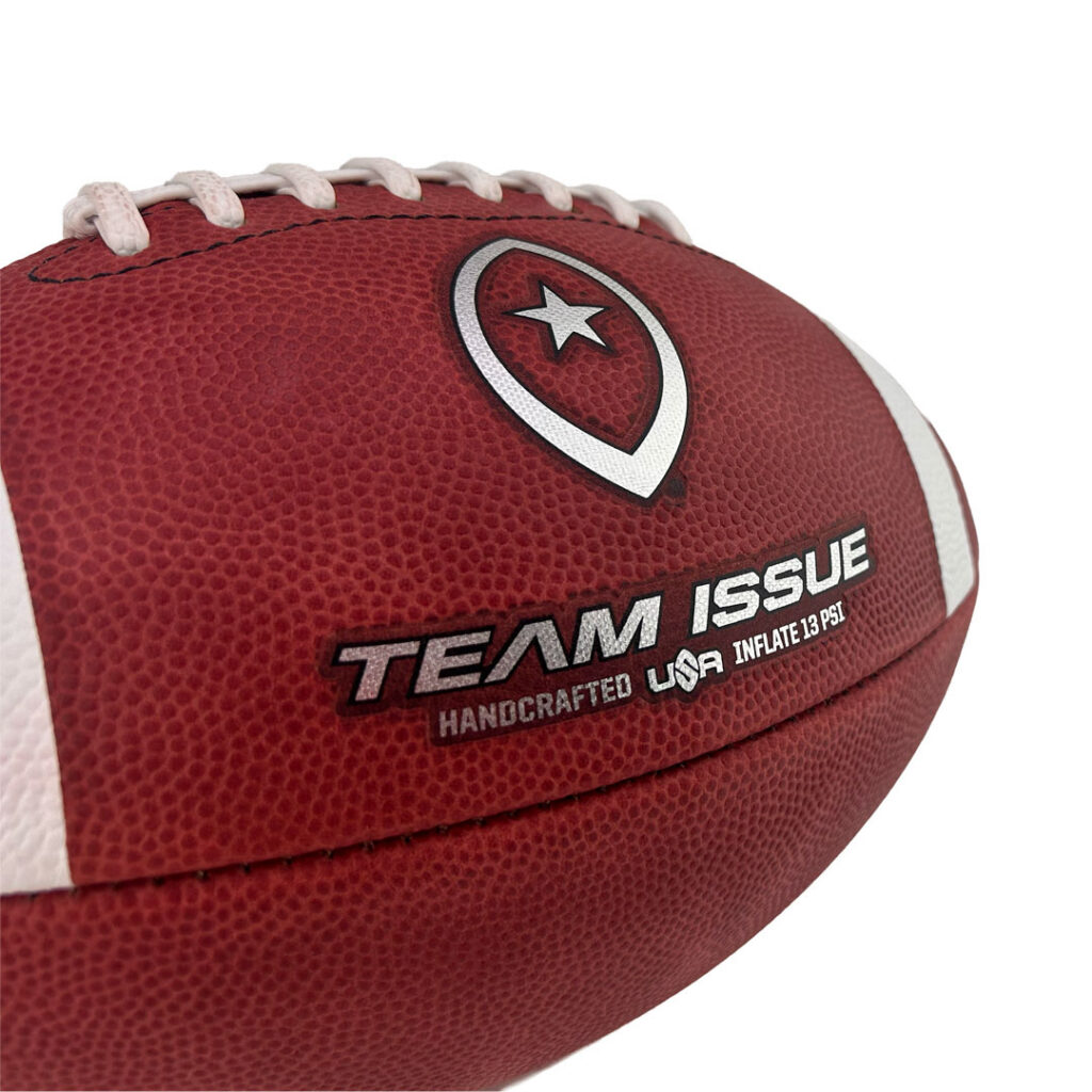 Close-up of a red leather football with white laces and a Team Issue logo on the panel.