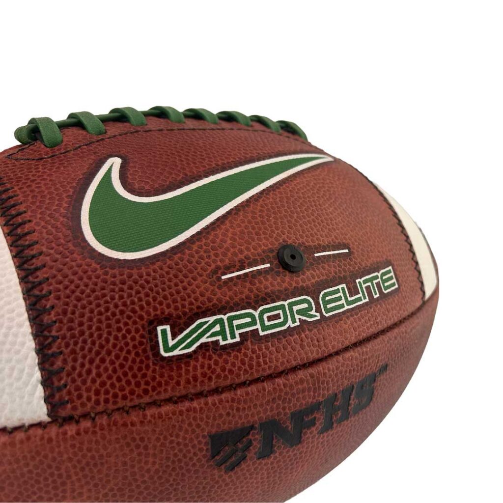 Close-up of a brown football with green laces and a green Nike Swoosh, showing the 'VAPOR ELITE' branding and white side panels.