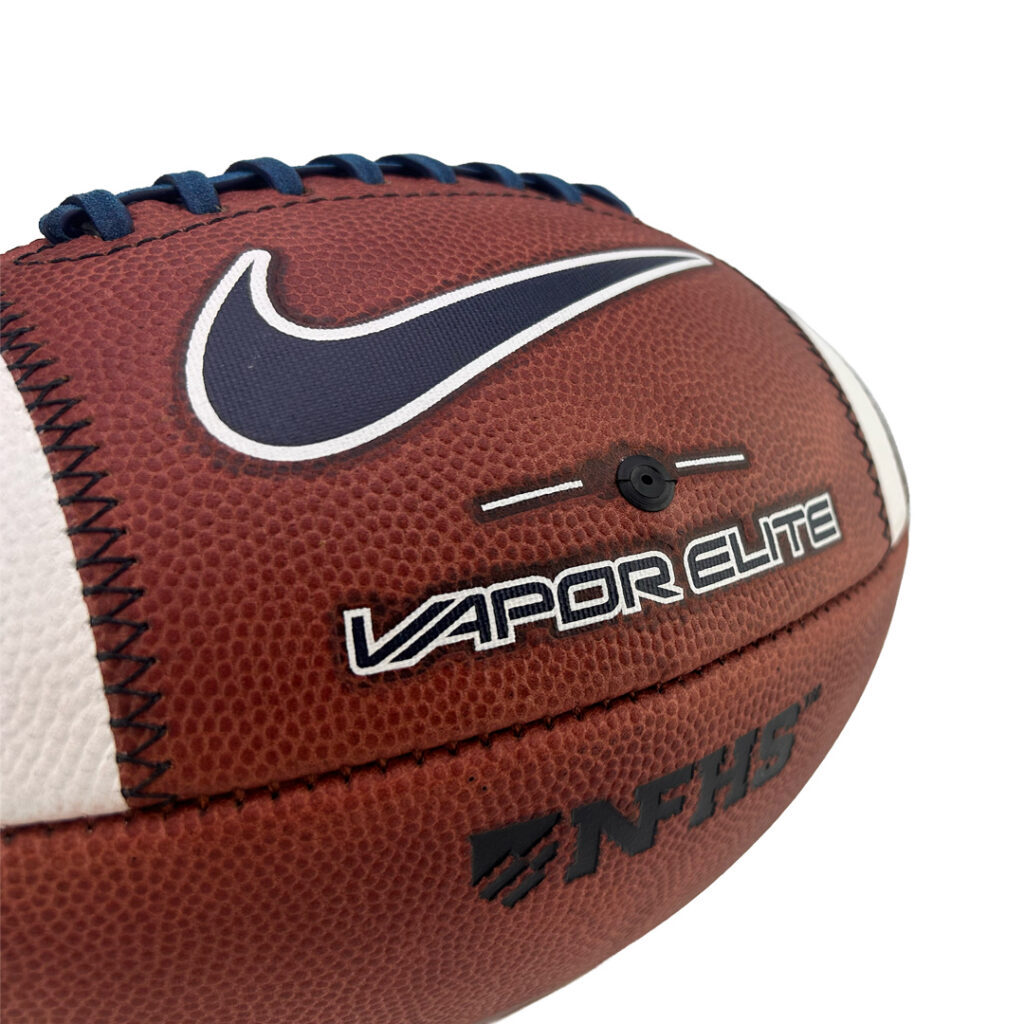 Close-up of a brown leather football with blue laces and white side panel, showing the Nike swoosh and 'Vapor Elite' branding.