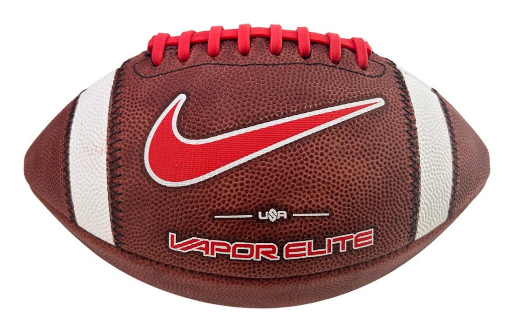 Brown American football with red Nike swoosh logo and red laces on white panels, labeled Vapor Elite USA (informative product image)