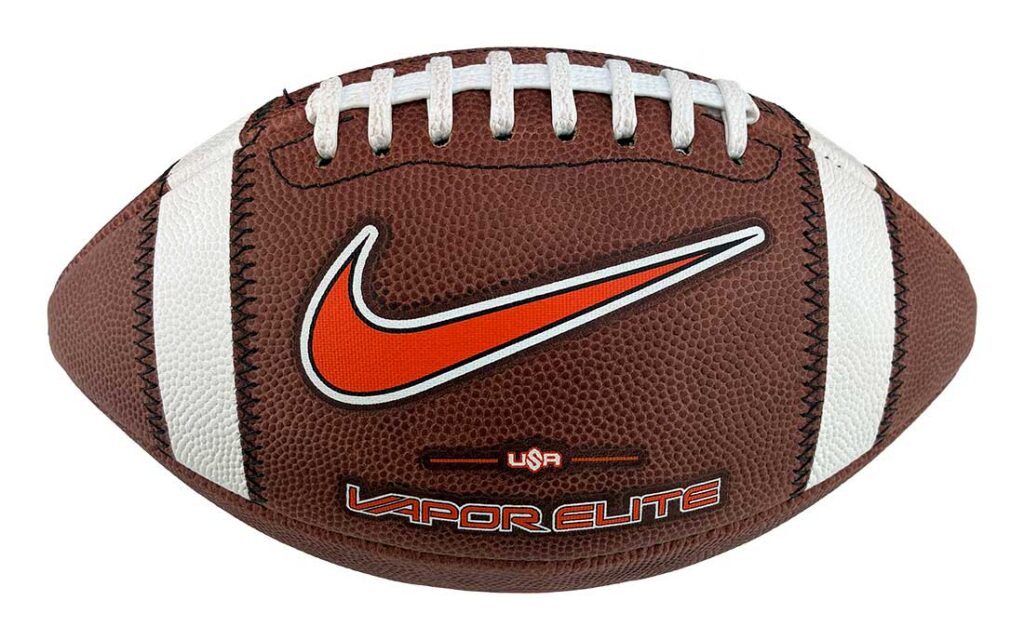 Brown football with white laces and stripes, prominent orange Nike swoosh logo in the center, and 'VAPOR ELITE' text at the bottom edge of the ball.