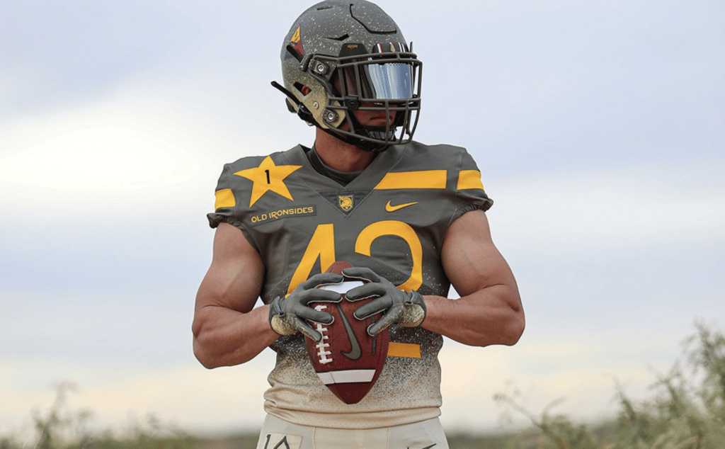 Image of Army Black Knights football player, outside, holding a football