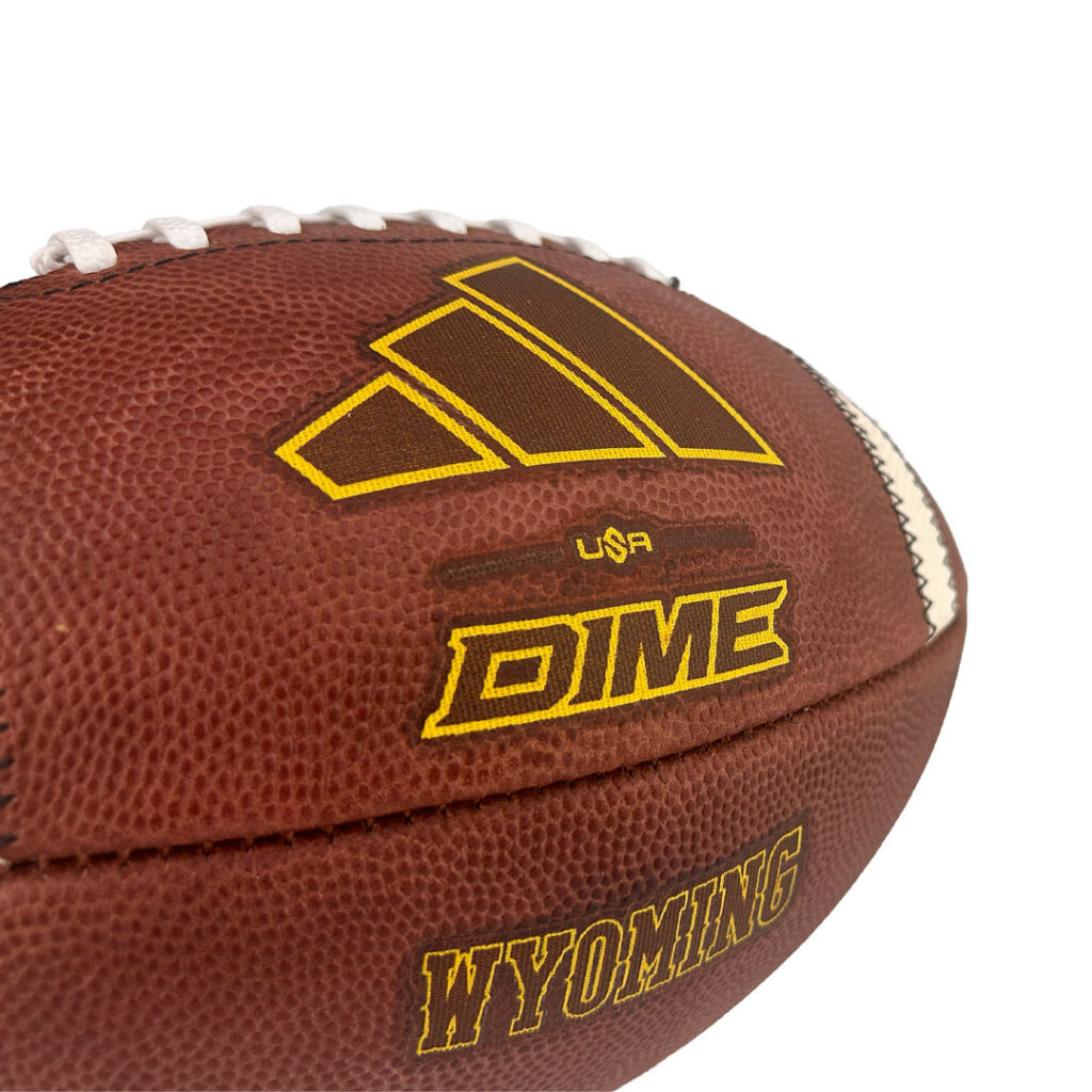 Close-up of a brown leather football with yellow branding, including the DIME logo and WYOMING text.