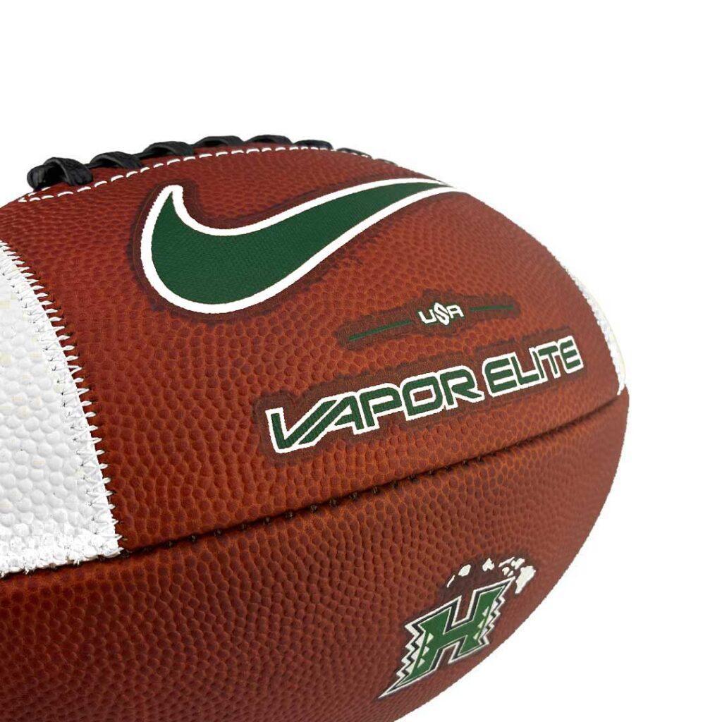 Close-up of a brown leather football with a green Nike swoosh, white stitching, and Vapor Elite branding.