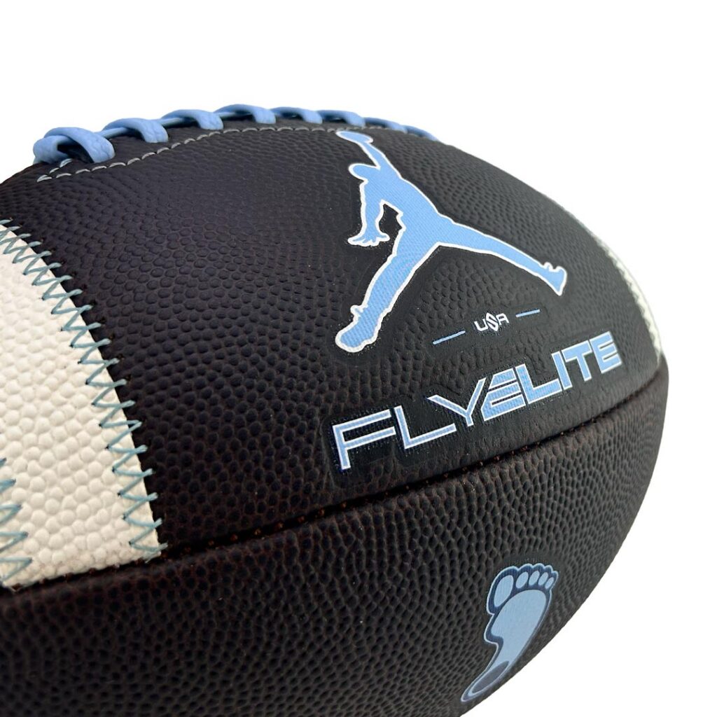 Close-up of a black Fly Elite basketball with blue laces and Jumpman silhouette, plus light blue 'FLYELITE' text and a small blue footprint at the bottom.