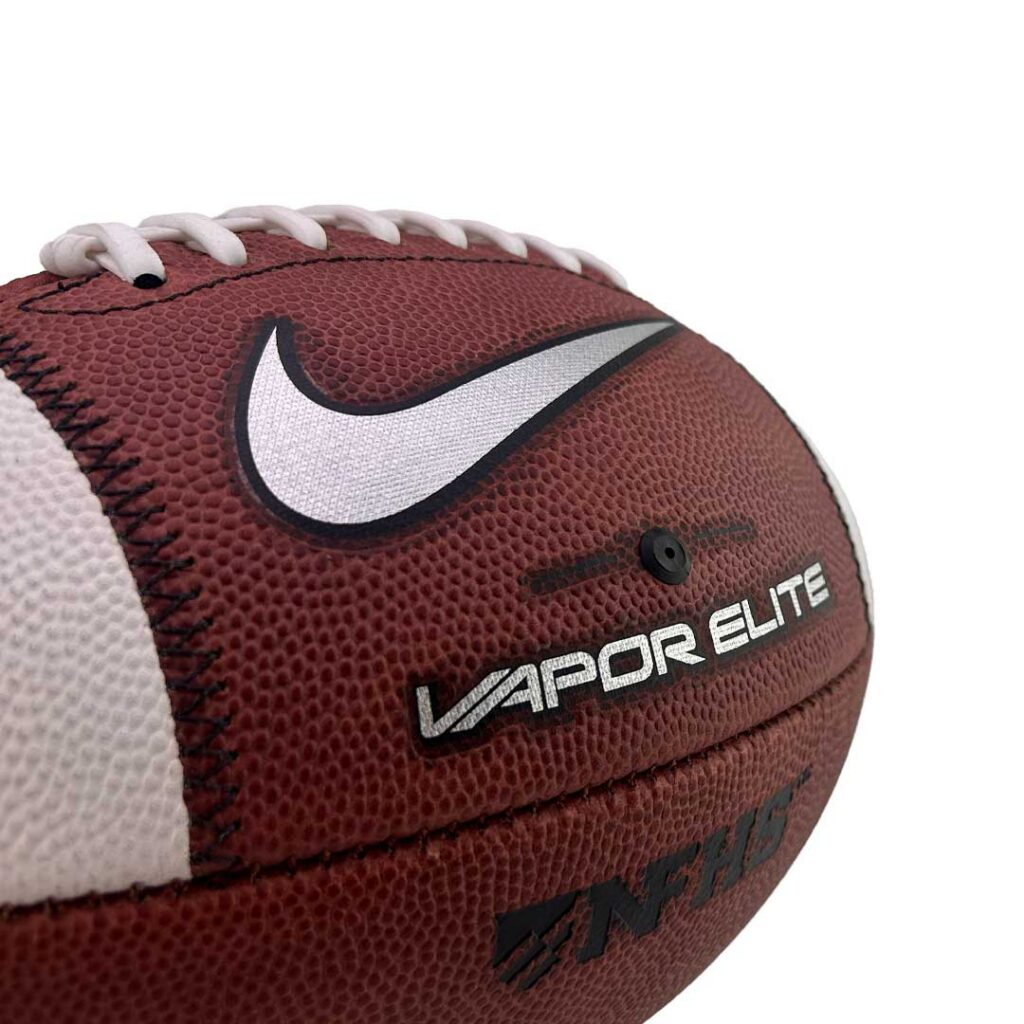 Close-up of a brown Nike Vapor Elite football showing white laces, white Nike swoosh, and textured surface.