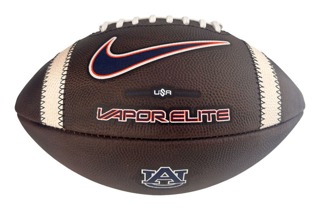 Brown leather football with white laces and cream side panels, features Nike swoosh, 'VAPOR ELITE' branding, and Auburn logo.