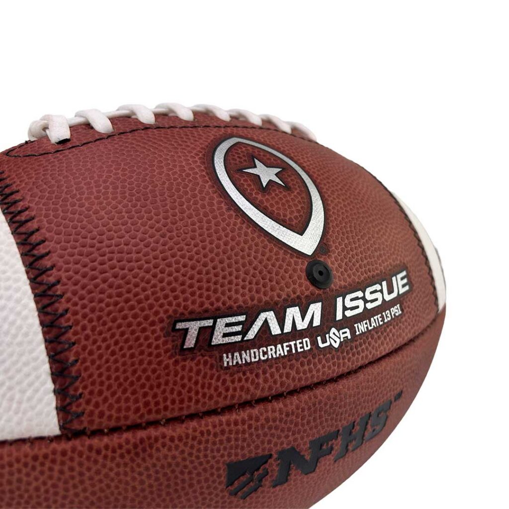 Close-up of a brown leather football with white laces and a silver star shield logo, showing Team Issue branding