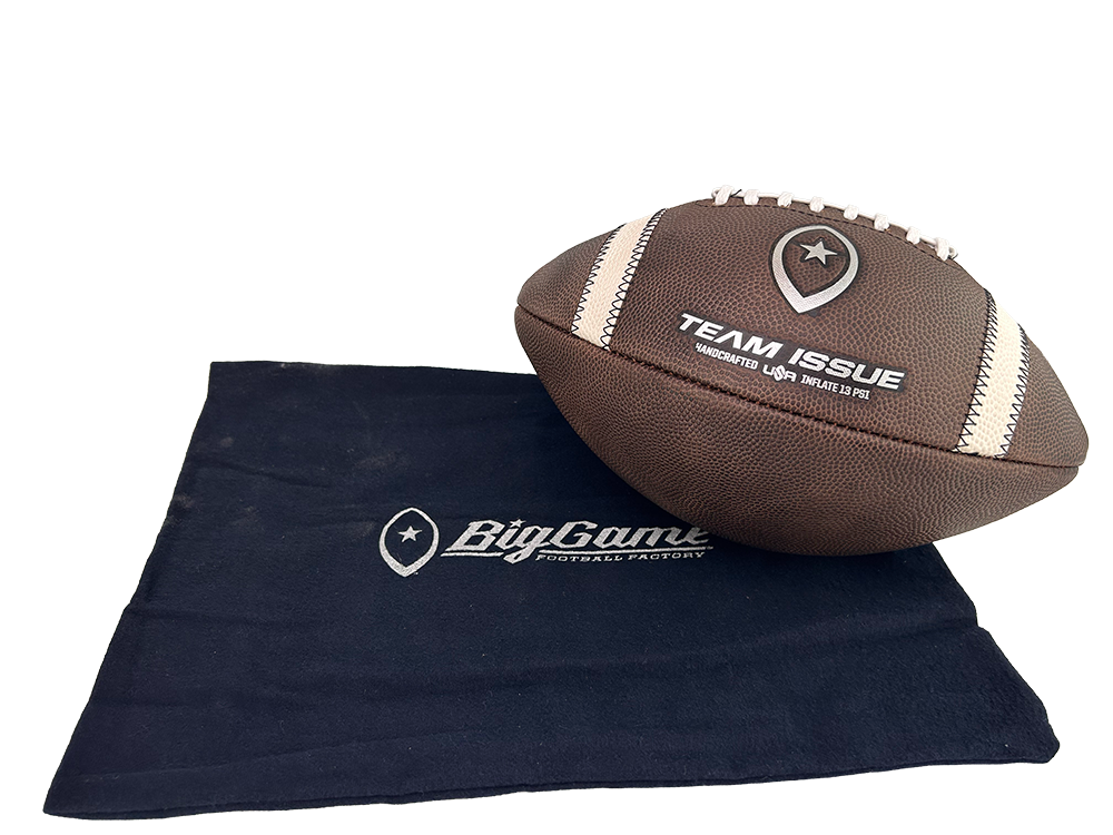 Brown leather football with white laces resting on a dark blue BigGame cloth/logo.