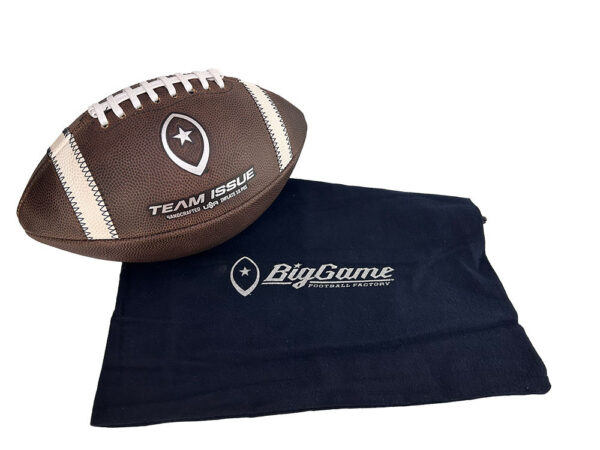 Brown leather football with white laces and Team Issue branding resting on a navy towel that reads BigGame Football Factory