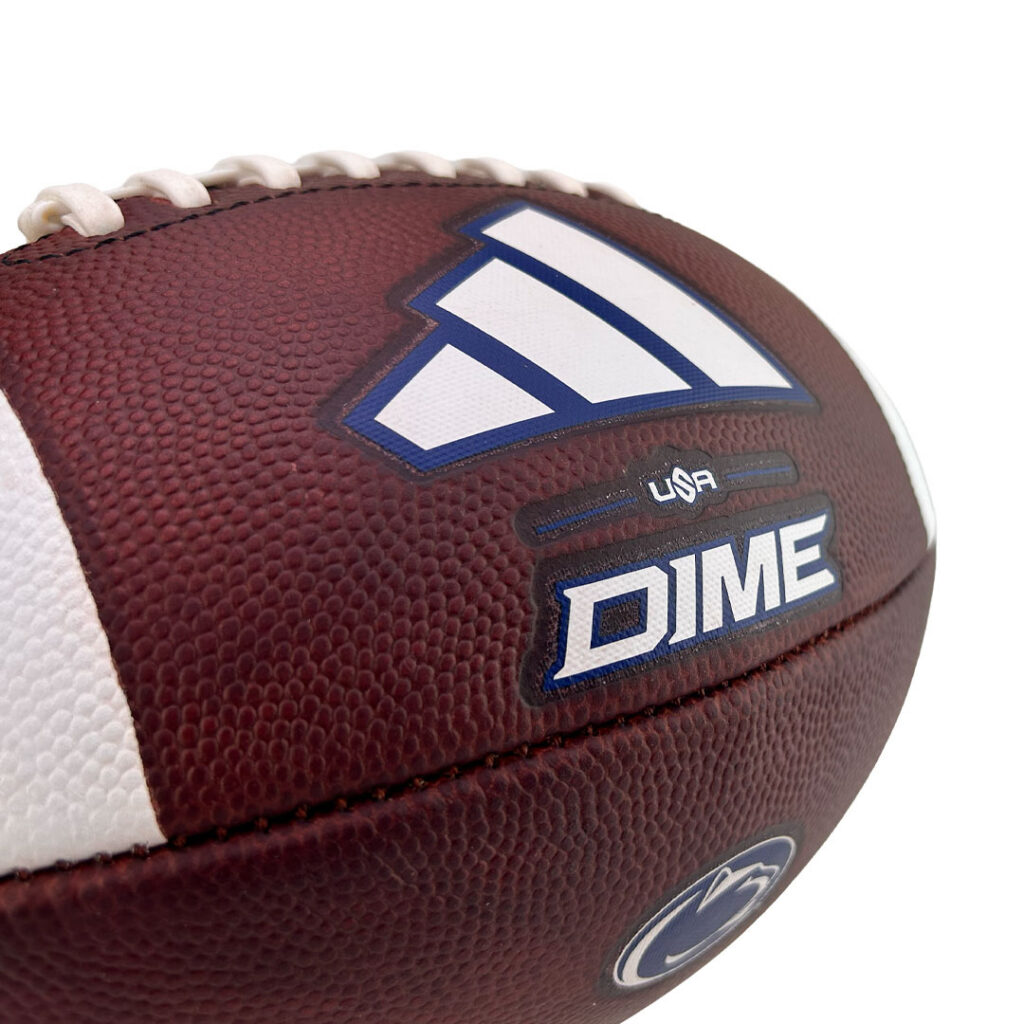Close-up of a brown American football with white laces, showing a blue-and-white logo and the word DIME on the surface.