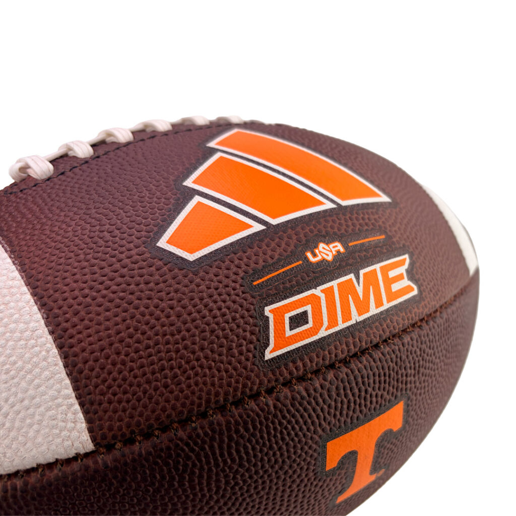 Close-up of a brown leather football with orange DIME logo and white laces, showing branding on the ball.