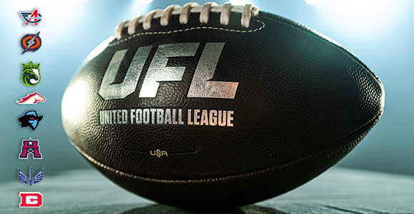 Close-up of a UFL football with 'United Football League' logo, spotlighted on a field; team logos run vertically along the left edge.