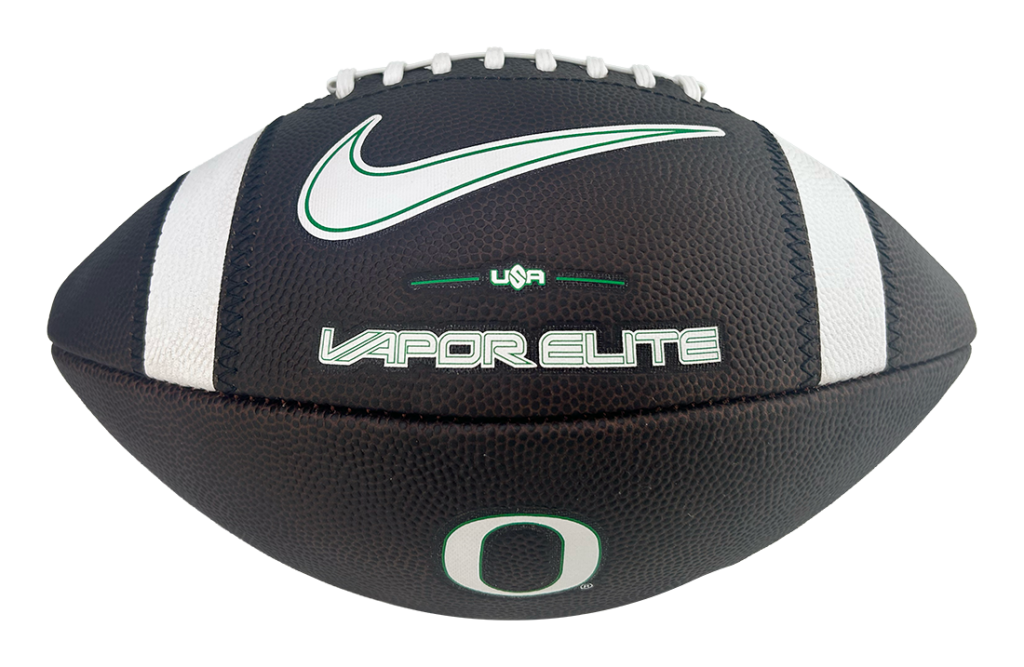 Close-up of a black Vapor Elite football with white stripes, white laces, and a green Nike swoosh plus an Oregon 'O' emblem.